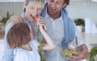 Young girl eating carrot with parents