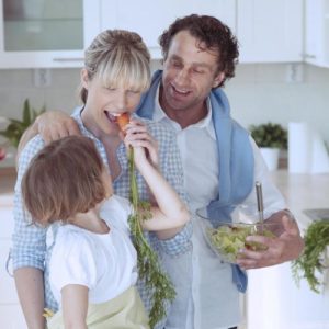 Young girl eating carrot with parents