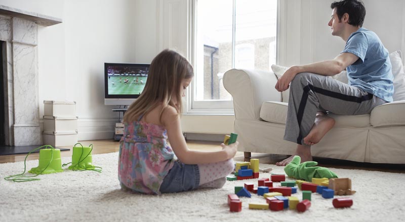 Girl Playing while Dad Watches Television